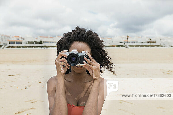 Junge Frau fotografiert durch eine alte Kamera am Strand