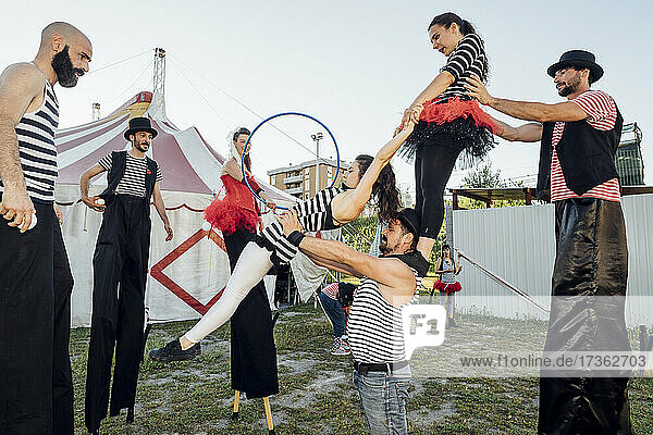 Zirkusakrobaten und Artisten üben miteinander hinter dem Zirkuszelt