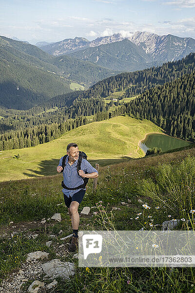 Älterer männlicher Wanderer mit Rucksack  der auf einem Berg wandert
