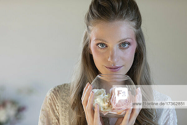 Beautiful blond woman holding scented roses in glass bowl