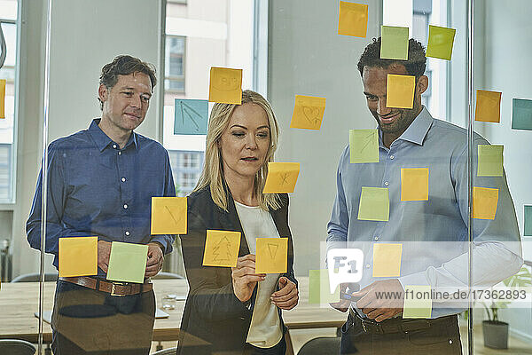 Business professionals planning strategy on adhesive notes in board room at office