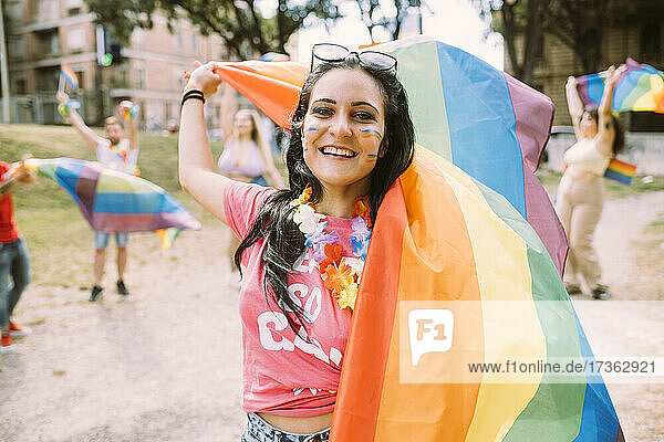 Glückliche Frau mit Regenbogenfahne bei Pride-Veranstaltung  um für Gleichberechtigung zu protestieren