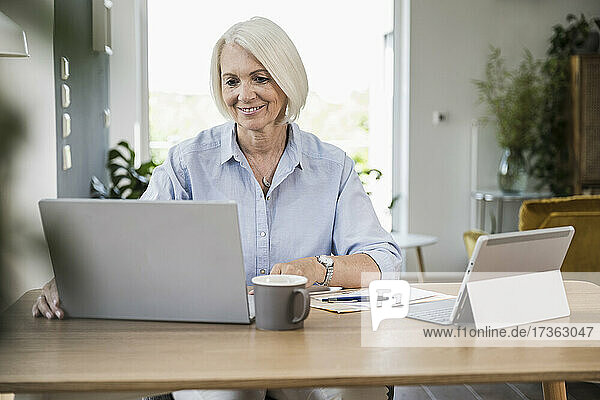 Reife Geschäftsfrau arbeitet am Laptop im Büro zu Hause