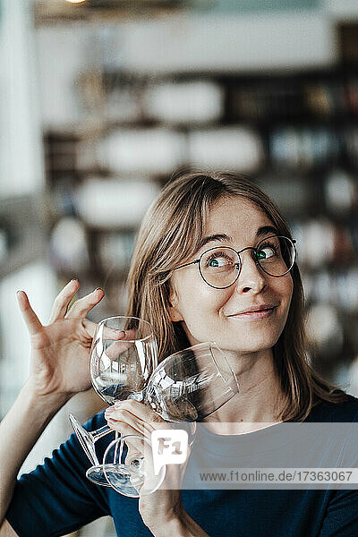 Junge Frau mit braunem Haar hält Weingläser in einem Cafe