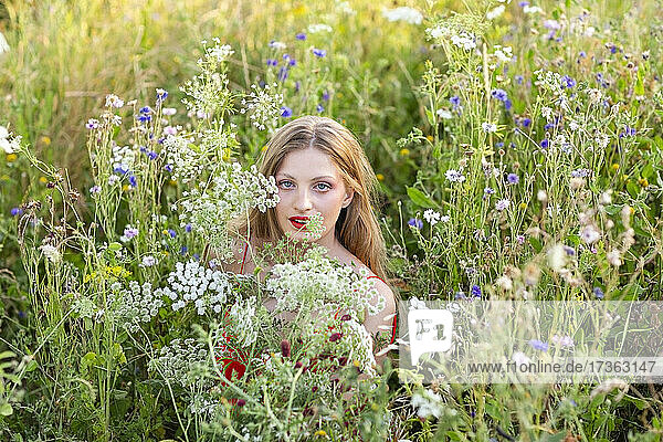 Beautiful woman amidst wildflowers in agricultural field