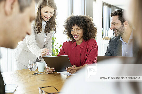 Geschäftsfrau nutzt digitales Tablet mit Kollegen in einer Besprechung im Büro