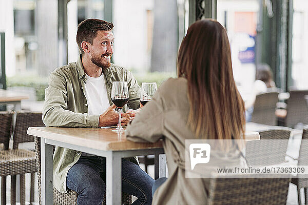 Happy man talking while looking at girlfriend in bar