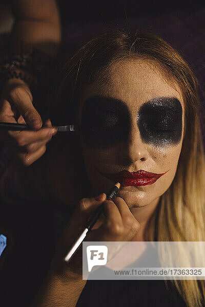 Friends doing make-up of woman during Halloween