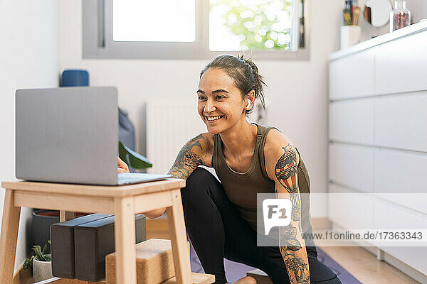 Glückliche Frau  die zu Hause mit ihrem Laptop e-Learning betreibt