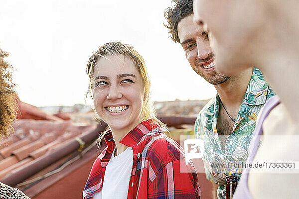 Happy young woman looking at friend on rooftop