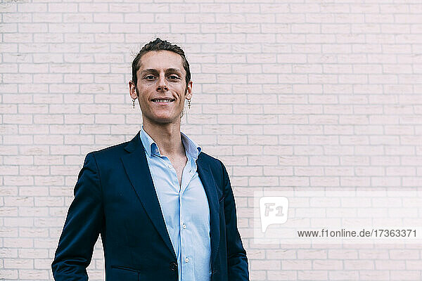 Smiling businessman standing in front of wall