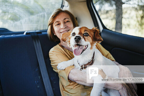 Ältere Frau mit Hund im Auto sitzend