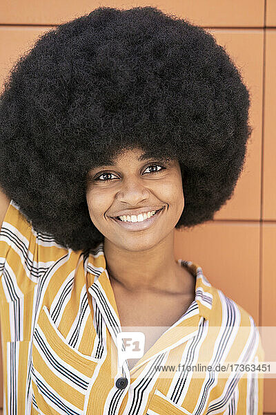 Afro-Frau lächelnd vor einer Wand