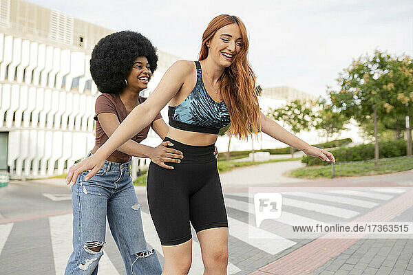 Happy Afro woman supporting redhead female friend