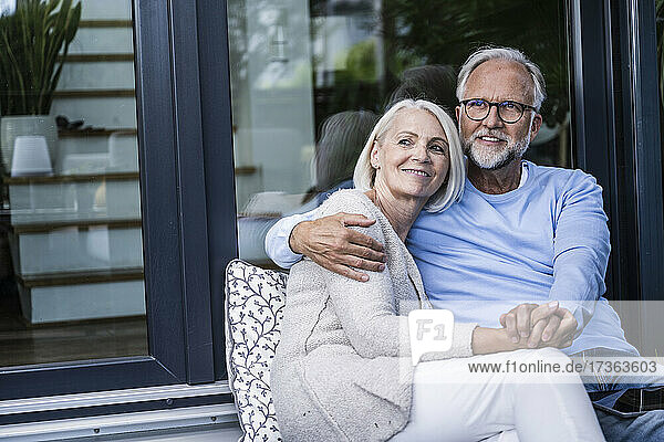 Nachdenkliches Paar hält sich an den Händen  während es auf dem Balkon sitzt