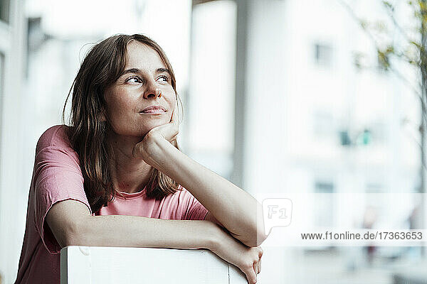Thoughtful woman sitting with hand on chin looking away