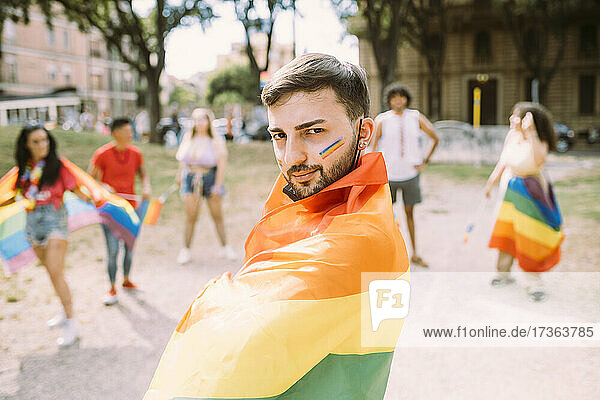 Mann mit Regenbogenfahne bei Pride-Veranstaltung eingewickelt