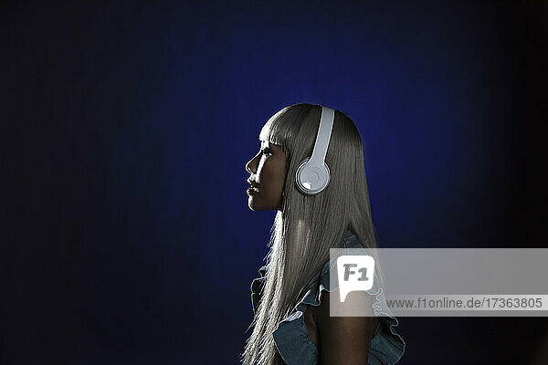 Junge Frau mit Kopfhörern vor blauem Hintergrund