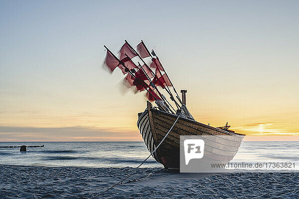 Einsames Fischerboot am Sandstrand bei Sonnenuntergang
