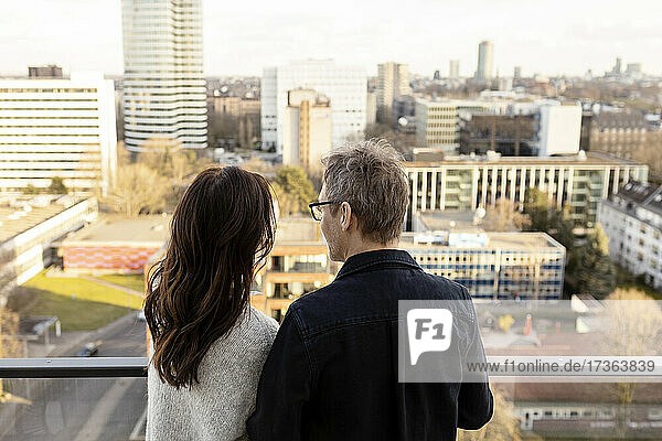 Älterer Geschäftsmann steht mit Geschäftsfrau auf dem Balkon eines Büros