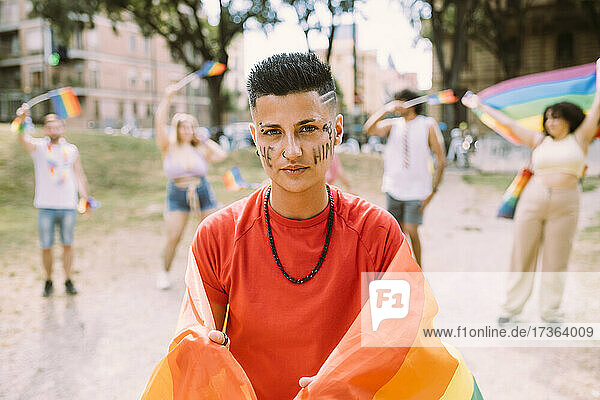 Junge Frau mit Regenbogenfahne protestiert bei einer Pride-Veranstaltung für Gleichberechtigung