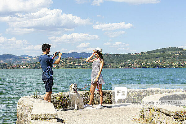 Freund fotografiert Freundin mit Hund auf der Seebrücke