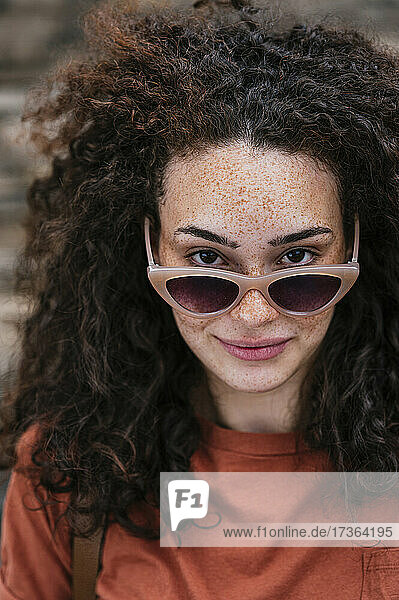 Schöne junge Frau mit lockigem Haar und Sonnenbrille