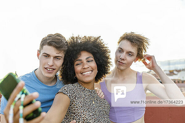 Männliche und weibliche Freunde nehmen Selfie durch Smartphone auf Terrasse