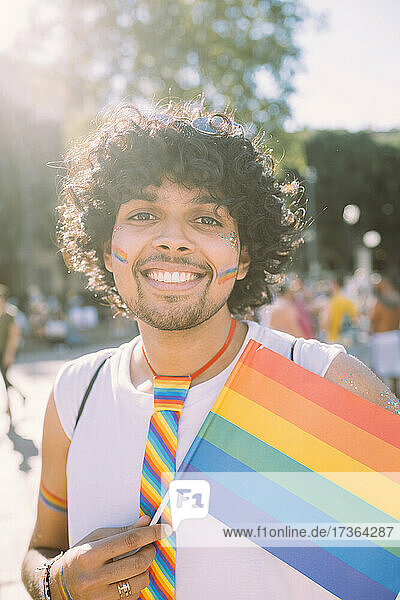 Smiling male protester with rainbow flag in pride event