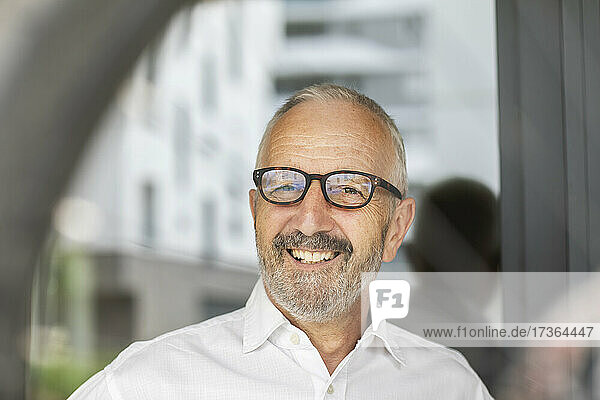 Lächelnder älterer männlicher Berufstätiger mit Brille