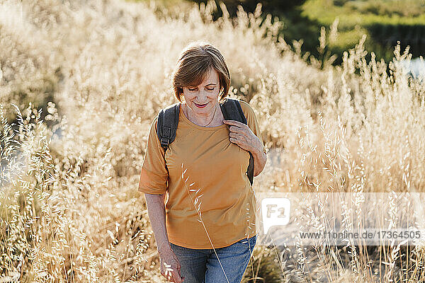 Ältere Frau mit Rucksack beim Wandern an einem sonnigen Tag