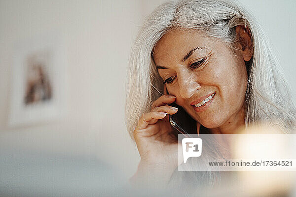 Geschäftsfrau  die im Büro mit einem Mobiltelefon spricht