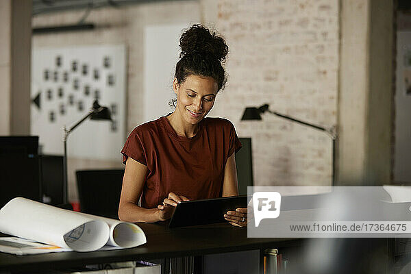 Female professional using digital tablet at desk in office