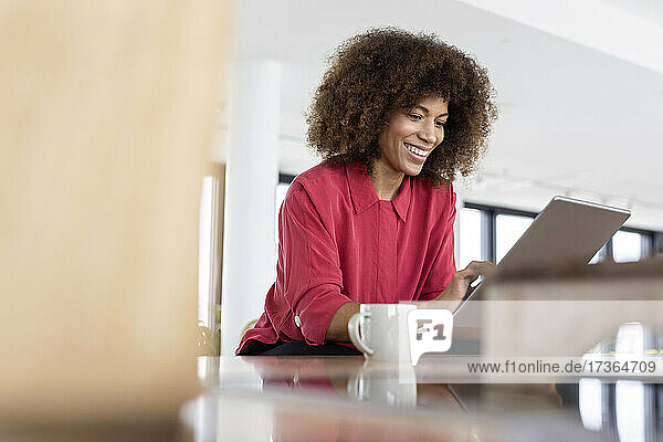 Berufstätige Frau  die am Arbeitsplatz sitzend ein digitales Tablet benutzt