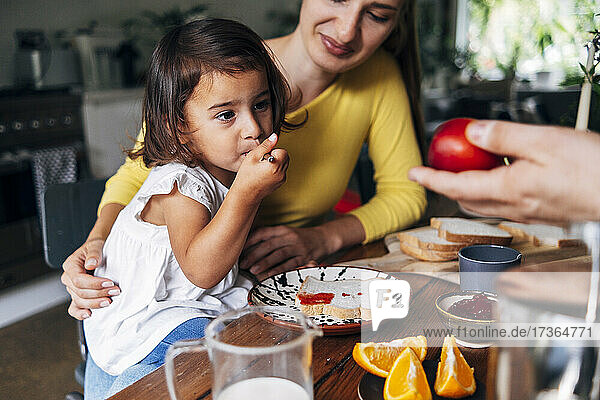 Man giving fruit to daughter having breakfast at home