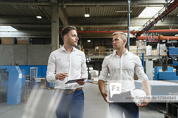 Männliche Fachleute diskutieren beim Gehen in einer Fabrik