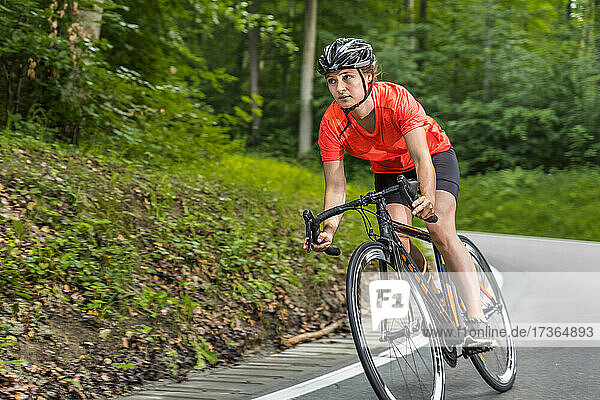 Weibliche Athletin fährt Fahrrad auf einer Straße im Wald