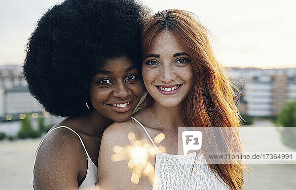 Lächelndes junges multiethnisches lesbisches Paar mit Wunderkerze