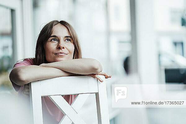 Nachdenkliche junge Frau  die sich in einem Café auf einen Stuhl stützt