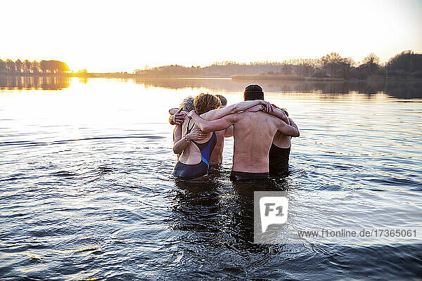 Männliche und weibliche Freunde  die sich umarmen und im Wasser klatschen