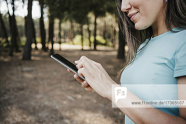 Junge Frau benutzt Mobiltelefon im Wald