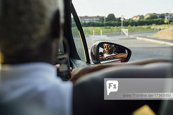 Reflexion einer Frau  die ein Telefon auf einem Autospiegel benutzt