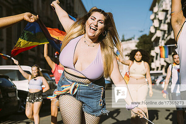 Fröhliche Frau mit männlichen und weiblichen Freunden protestiert an einem sonnigen Tag bei einer Pride-Veranstaltung