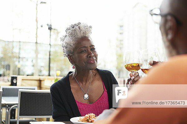 Lächelnde Frau stößt mit einem Mann im Restaurant auf ein Getränk an