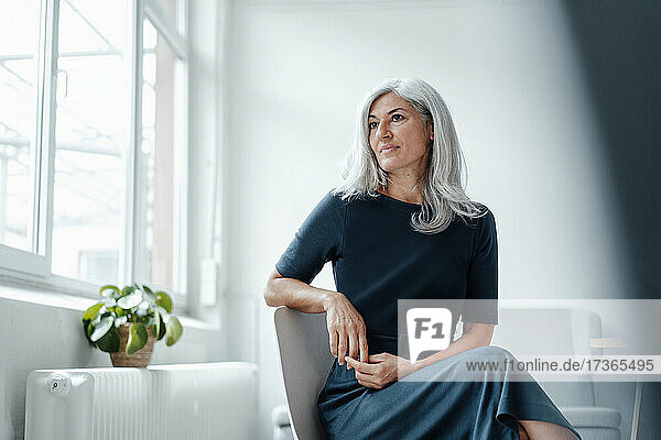 Female professional with white hair contemplating at office