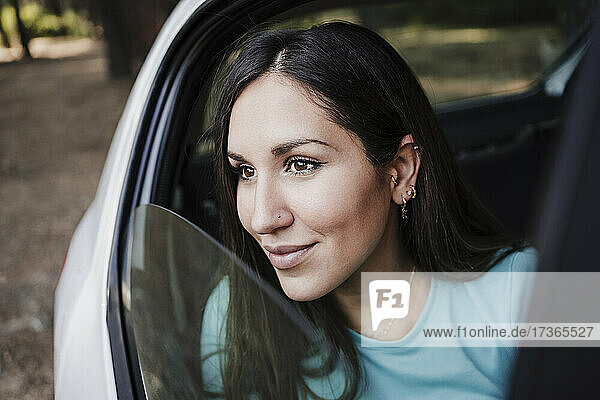 Beautiful young woman looking through car window
