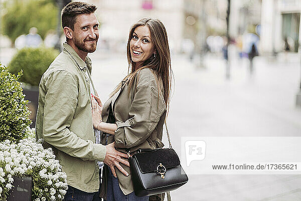Lächelnde Frau und Mann stehen bei Blumen