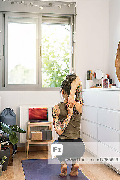 Frau streckt die Arme beim Online-Yoga zu Hause