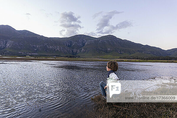 A boy exploring the shore of a lagoon in the shadow of the Kleinriver mountain range