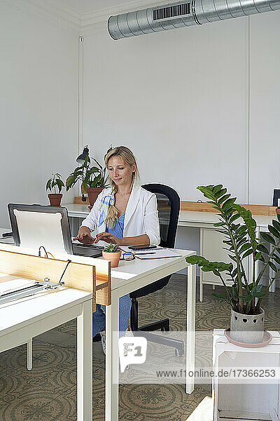 Mid adult businesswoman working on laptop at office